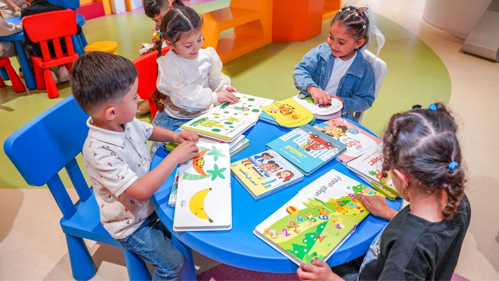 Kleine Kinder sitzen an einem Tisch und blättern gemeinsam in Bilderbüchern